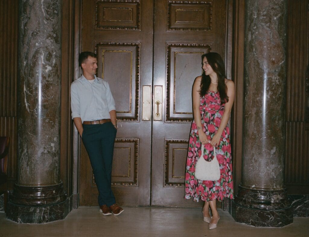 Engaged couple takes photo by double doors for their engagement photo shoot
